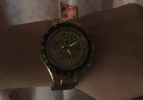 Winner mechanical skeleton sports watch with gold-tone case and bracelet, black bezel, glowing green hands
