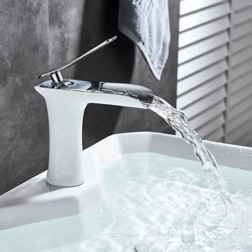 Basin faucet with chrome finish and single-handle waterfall spout, mounted on a modern bathroom sink.