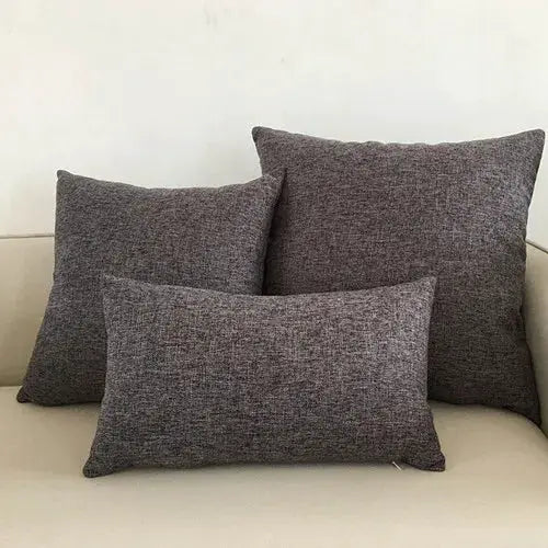 Three grey textured sofa cushions on a beige sofa; decorative pillow covers