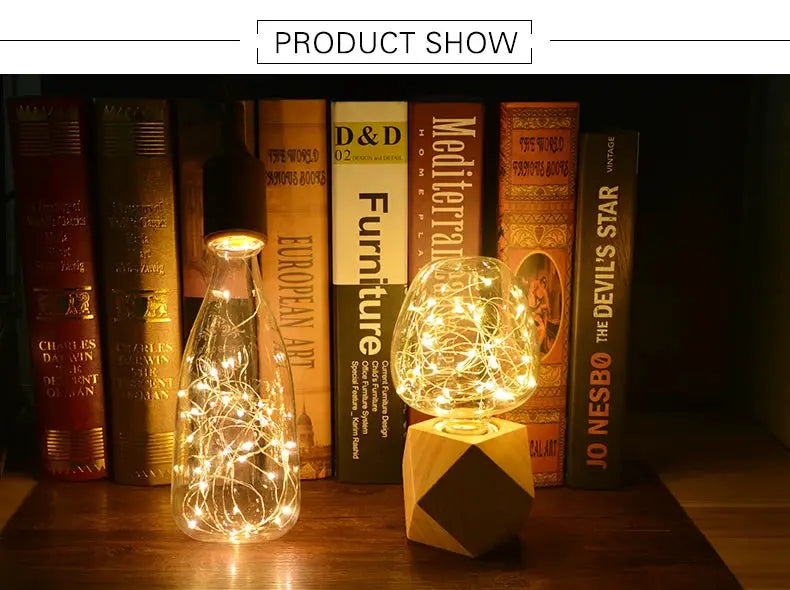 Two decorative lamps: a glass bottle lamp with warm string lights and a spherical glass lamp on a wooden geometric base