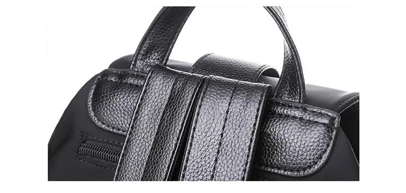 Black nylon women’s backpack with top handle and padded straps, featuring a zipper pocket.