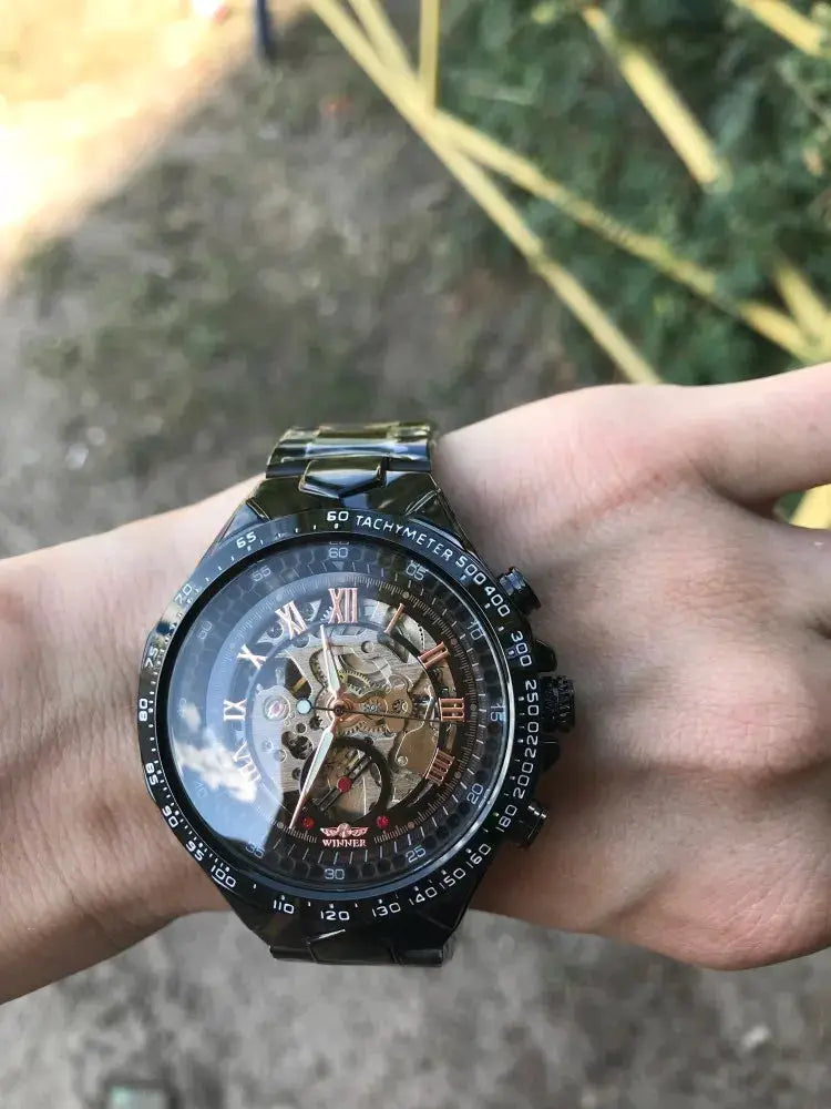 Winner mechanical skeleton men's watch with black stainless steel band and tachymeter bezel.