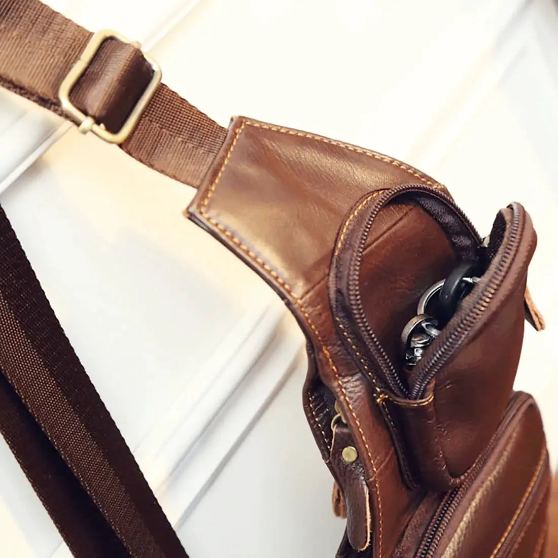 Men's brown genuine leather crossbody sling bag with zip pockets and adjustable strap.
