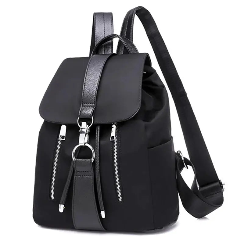 Black nylon women’s backpack with fold-over flap, two front zip pockets, and adjustable straps