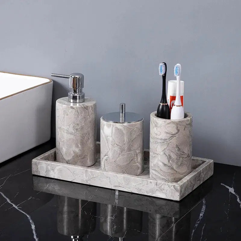 Gray marble bathroom accessories set with liquid soap dispenser, canister, and toothbrush cup on a tray