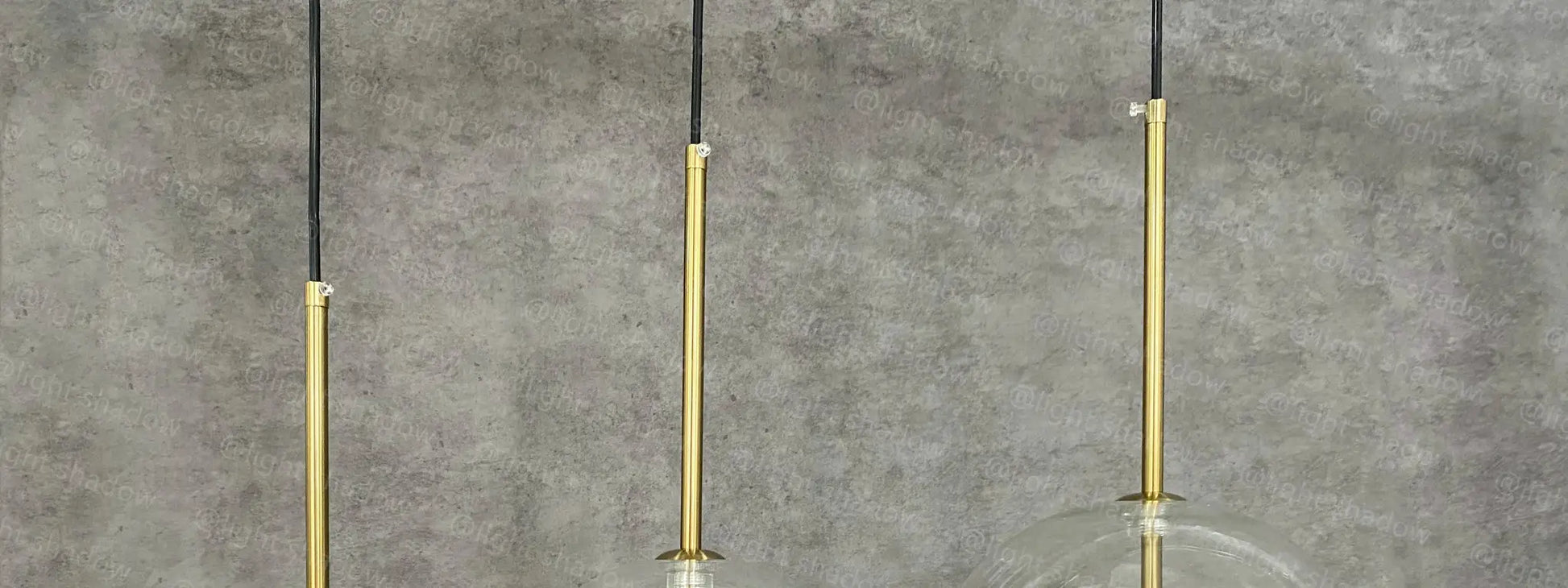 Three-light LED pendant lamp with glass ball globes, gold finish and black cords by Simples Market