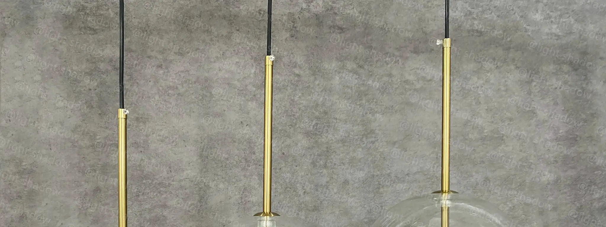 Three-light LED pendant lamp with glass ball globes, gold finish and black cords by Simples Market