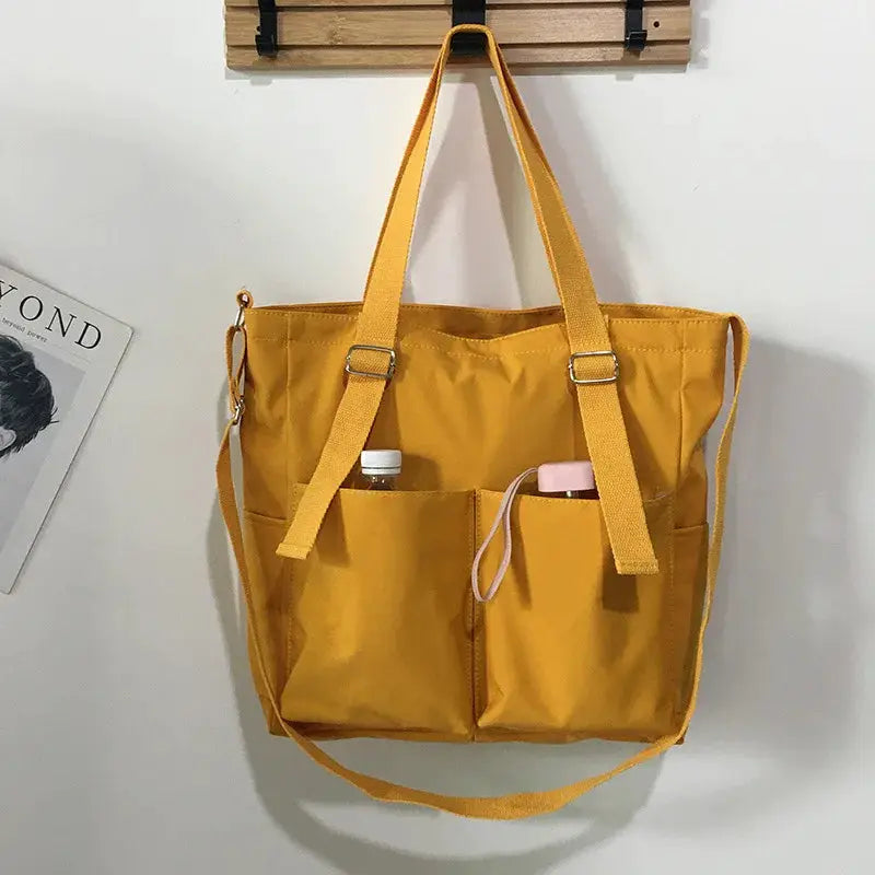 Simples Market waterproof Oxford large-capacity handbag for women; mustard yellow with dual handles and front pockets.