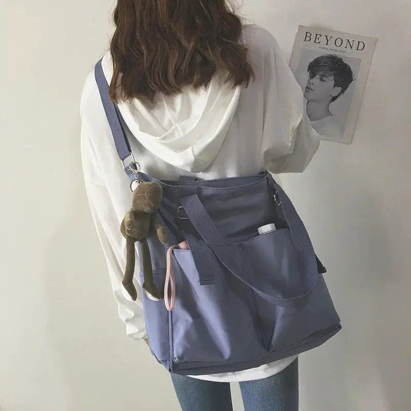 Waterproof Oxford large-capacity lavender women's handbag with shoulder strap, front pockets, and a plush keychain.