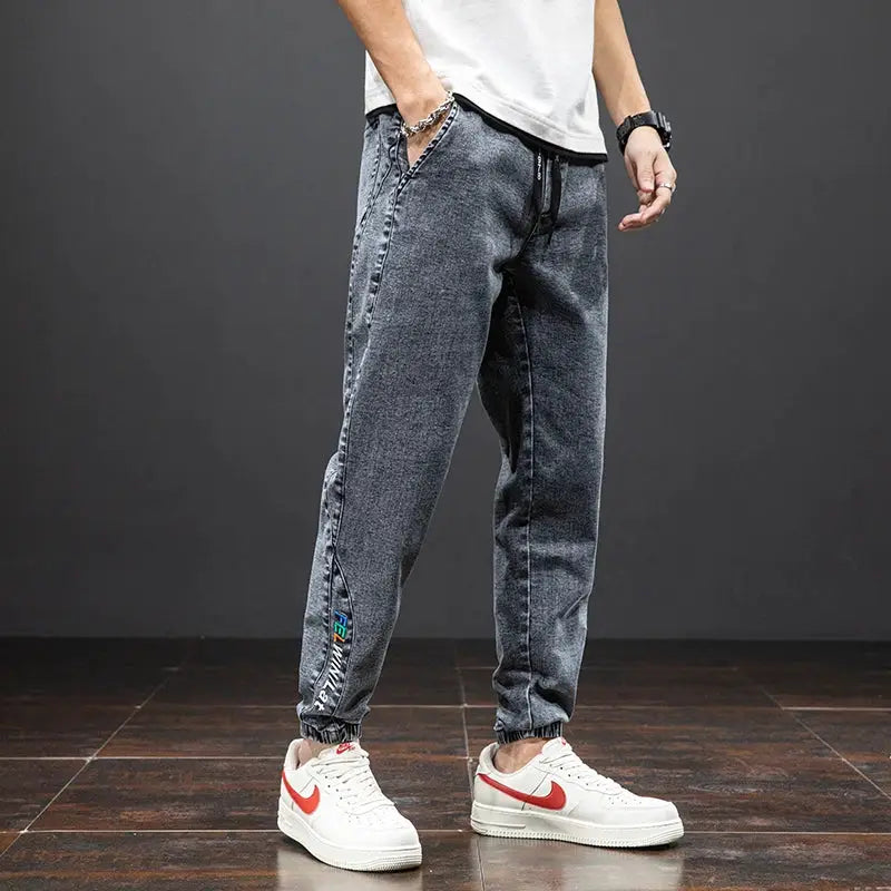 Men's baggy cargo denim jogger jeans with drawstring waist and elastic cuffs in dark wash