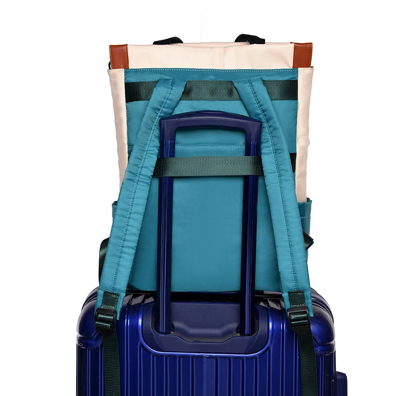 Backpack, waterproof Oxford, teal color with teal straps, shown with a blue rolling suitcase