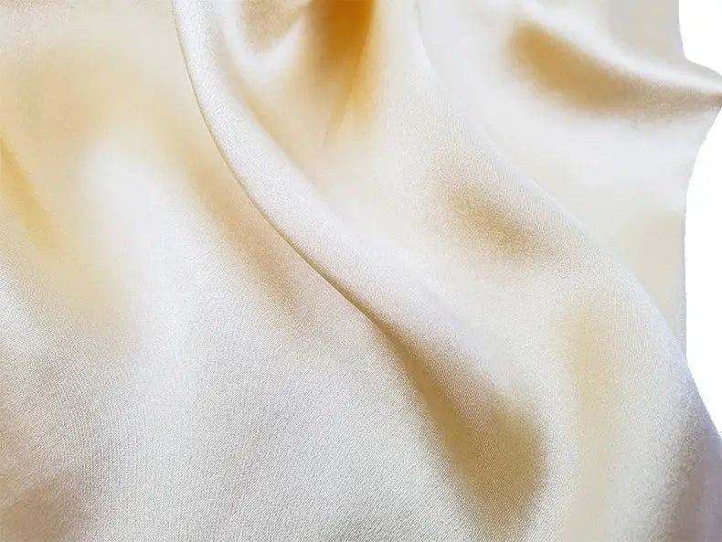 SuyaDream white silk shorts fabric close-up with smooth satin texture.