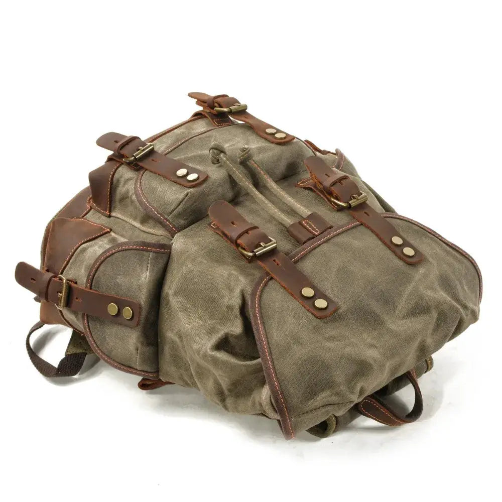 Vintage canvas backpack with brown leather straps, brass hardware, olive waxed fabric, men's travel rucksack