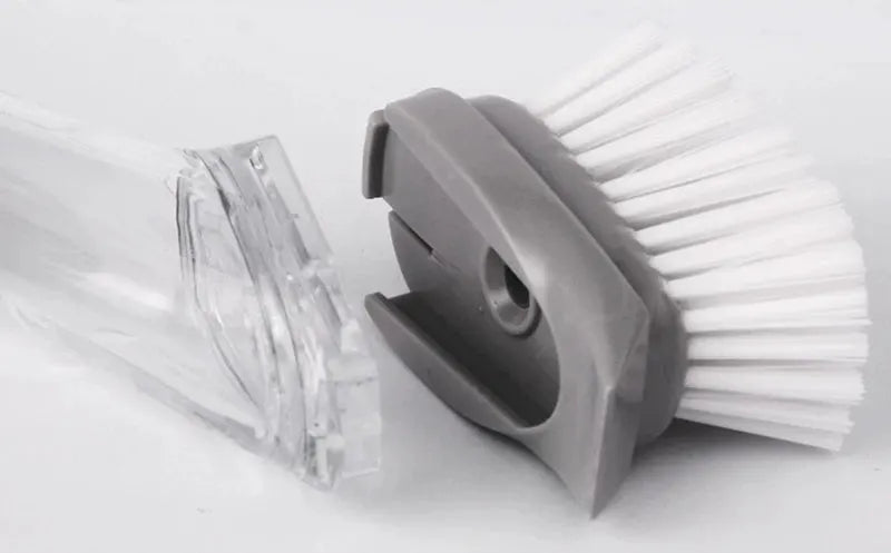 Refillable liquid cleaning brush with transparent reservoir and grey dispenser, white bristles.