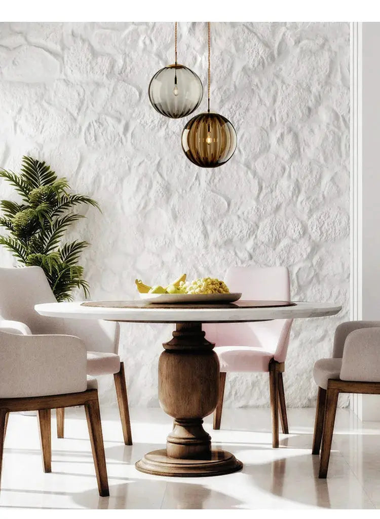Modern LED glass ball pendant lights; two amber and smoky gray globes over a round marble dining table