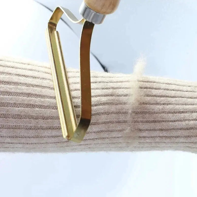 Portable lint remover tool with a gold metal head and wooden grip for removing lint from fabric