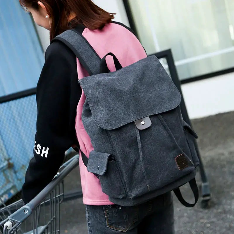 Dark grey canvas backpack; large school-style rucksack with flap closure.