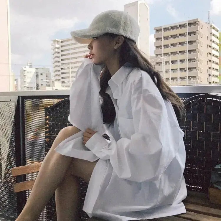 Zadily white oversized long-sleeve button-up shirt worn by woman on balcony, minimalist chic style