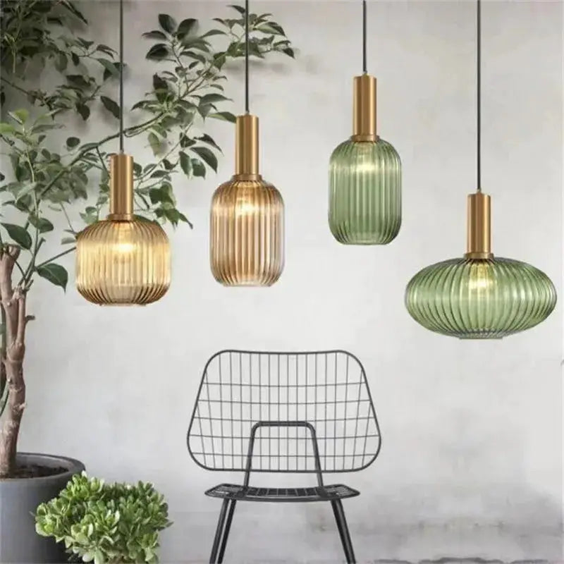Glass pendant lights, four retro fixtures in amber, ribbed and green tones, hanging over a wire chair.