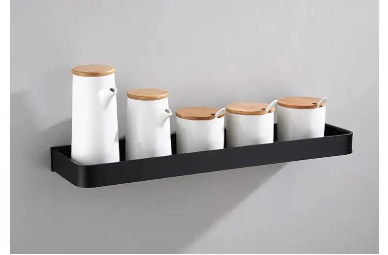 Bathroom wall-mounted black aluminum shelf holding five white canisters with wooden lids