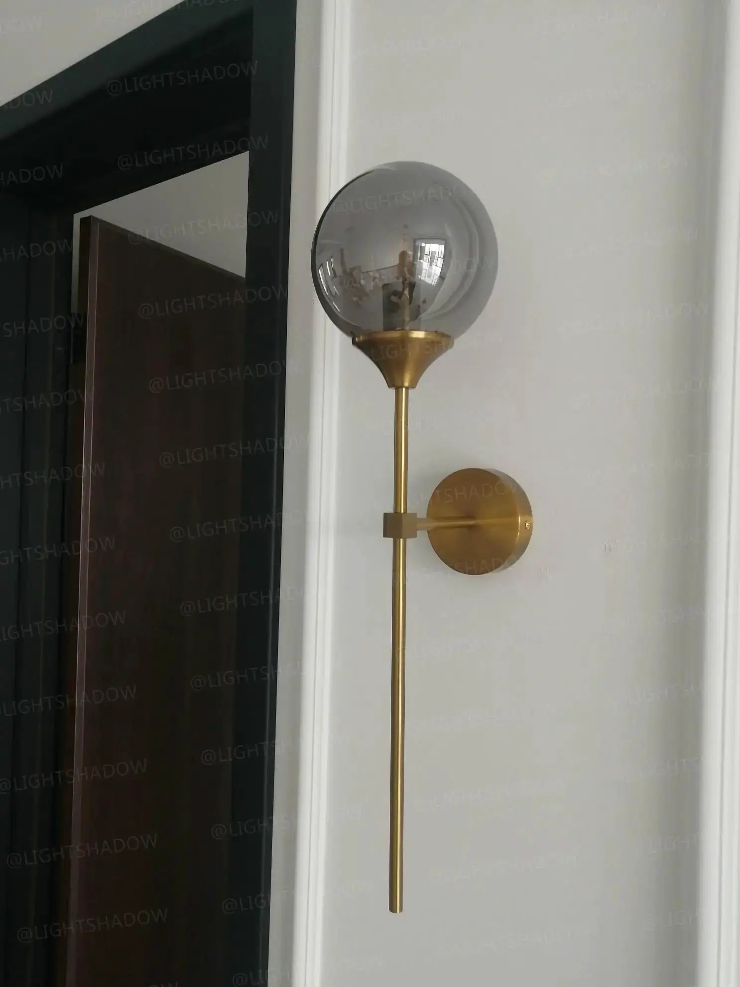 Modern glass wall lamp with a brass gold finish and a round glass shade, Simples Market.