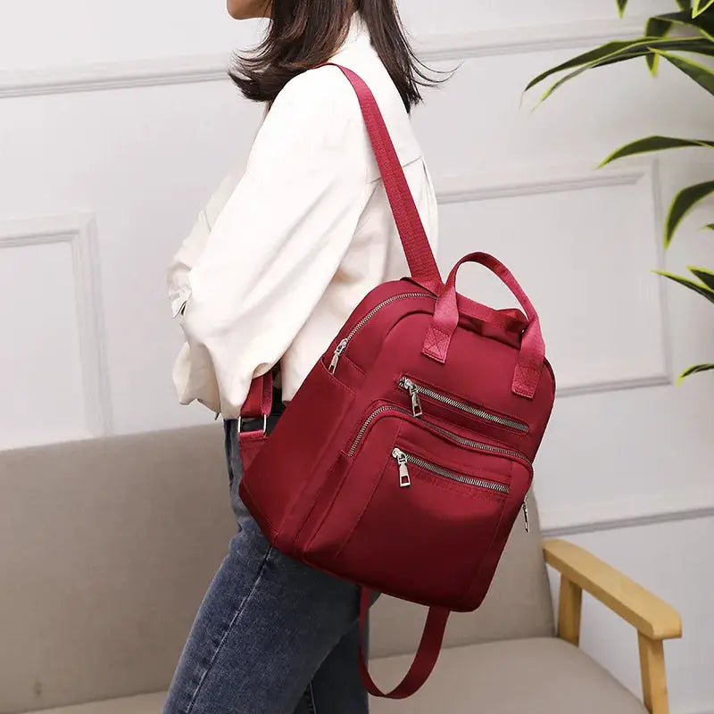Women's red backpack by Simples Market with multiple zip pockets and adjustable shoulder straps