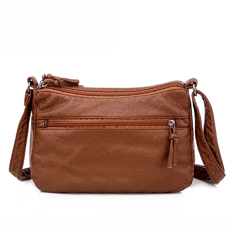 Women messenger bag in brown PU leather with crossbody strap and front zipper pocket.