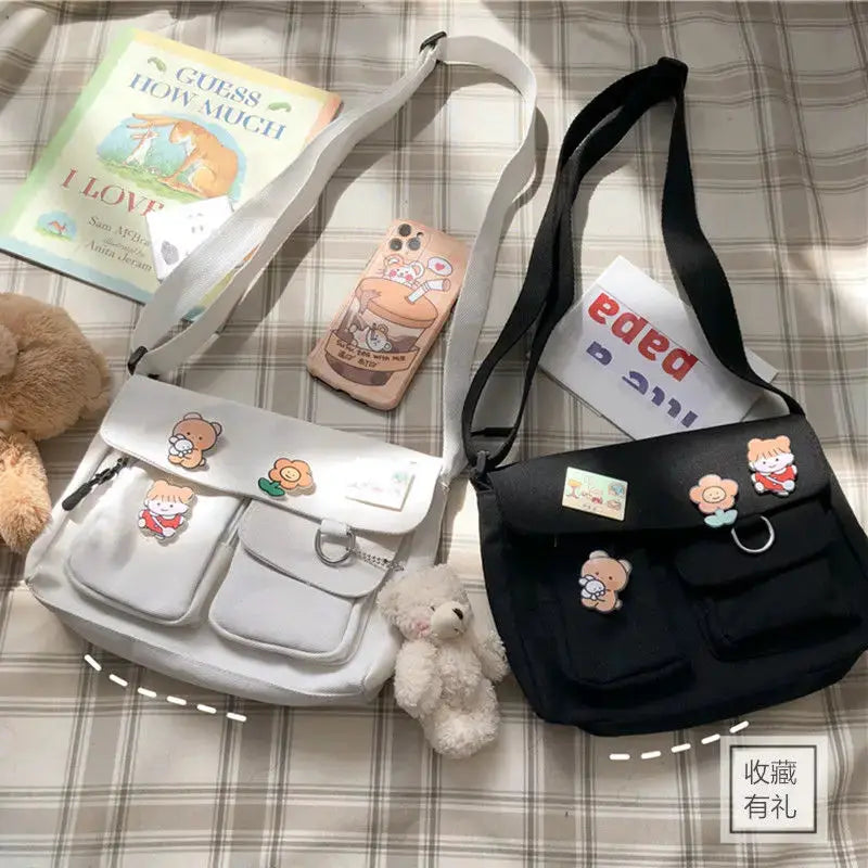 Simples Market canvas messenger bags, white and black with cartoon bear patches and front pockets, crossbody straps.