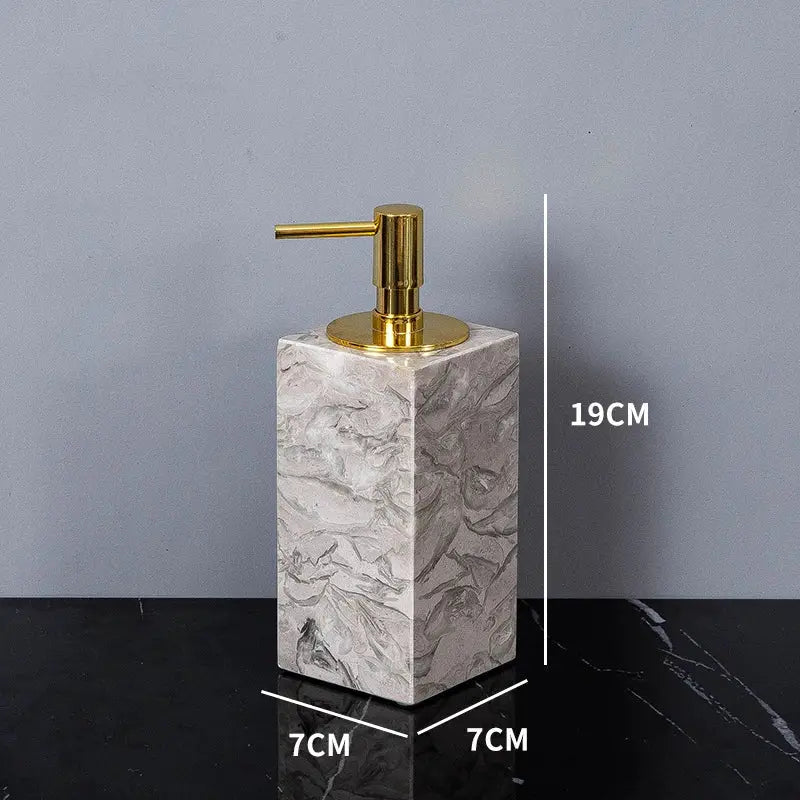 Bathroom soap dispenser in natural marble with a gold-toned pump on a 7 cm square base, 19 cm tall.