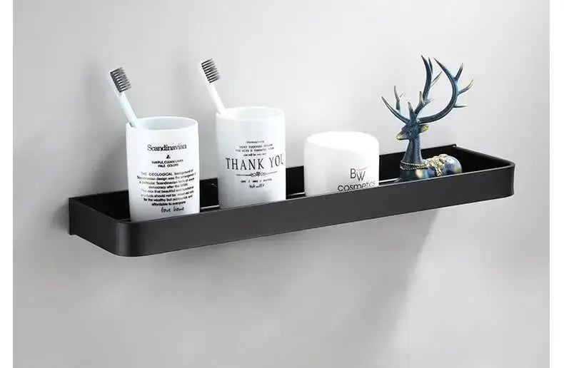 Wall-mounted black aluminum bathroom corner shelf with three white containers and a decorative deer statue