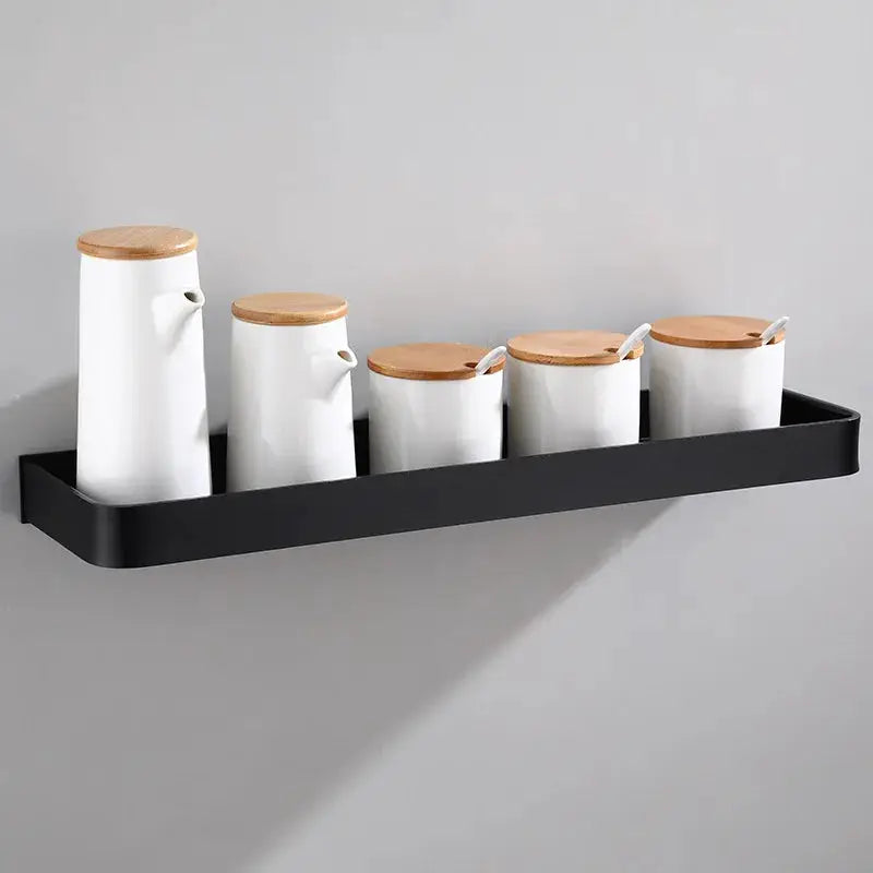 Wall-mounted black aluminum bathroom shelf with five white canisters and wooden lids