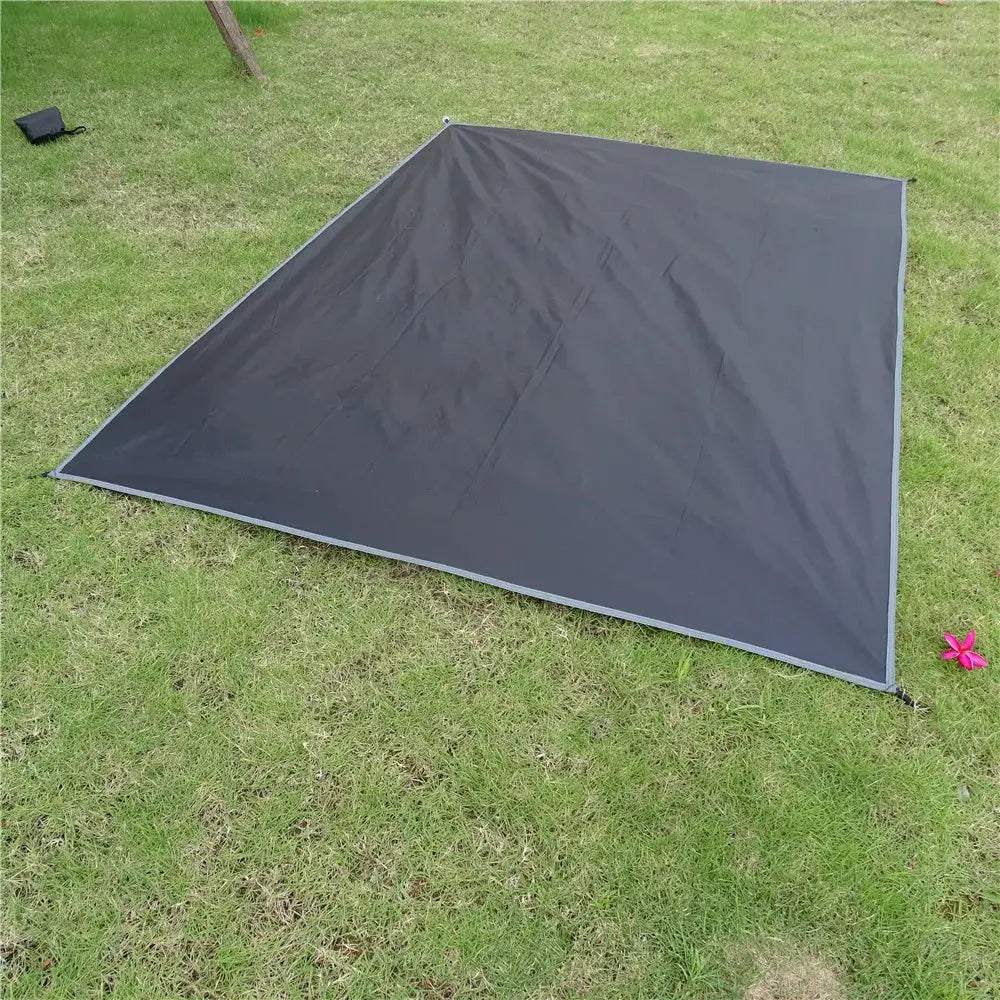 Waterproof Camping Mat by Simples Market in dark gray laid on grass with carry bag nearby