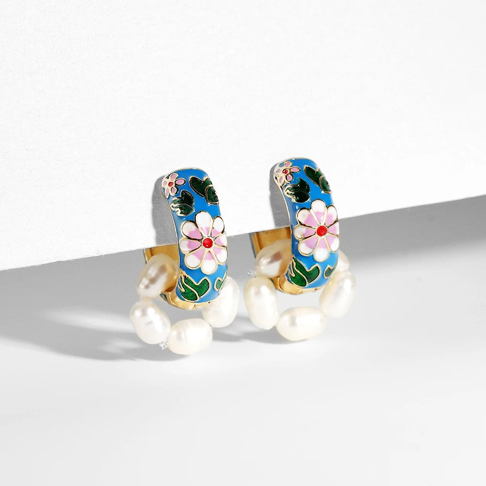 Pair of Simples Market enamel flower huggie hoops with blue enamel, white daisy petals, pink centers, and pearl accents