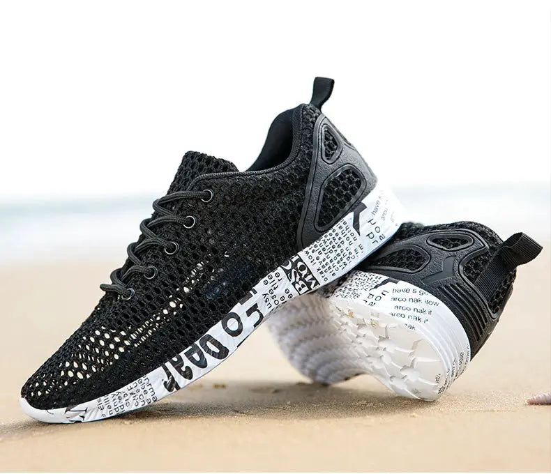 Pair of black breathable mesh sneakers with a white printed foam sole and heel pull tab