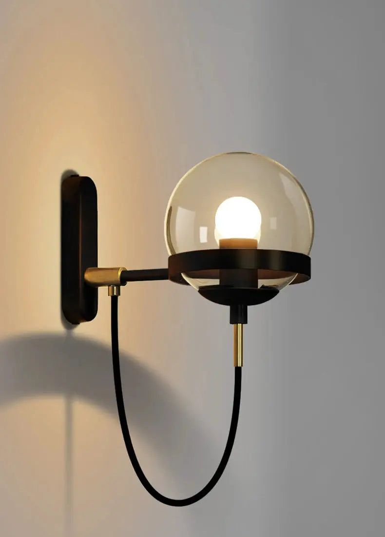 Modern glass globe wall lamp with black metal arm and brass accents, wall-mounted