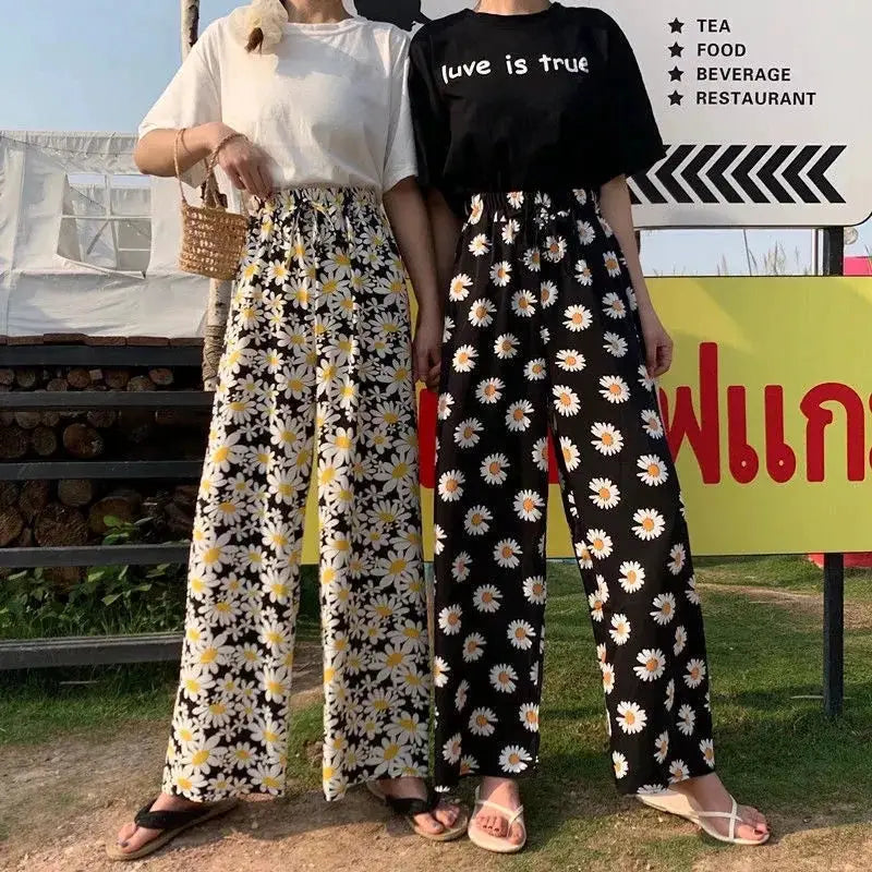 Daisy-print wide-leg pants on two models paired with white or black tees for casual vacation outfits
