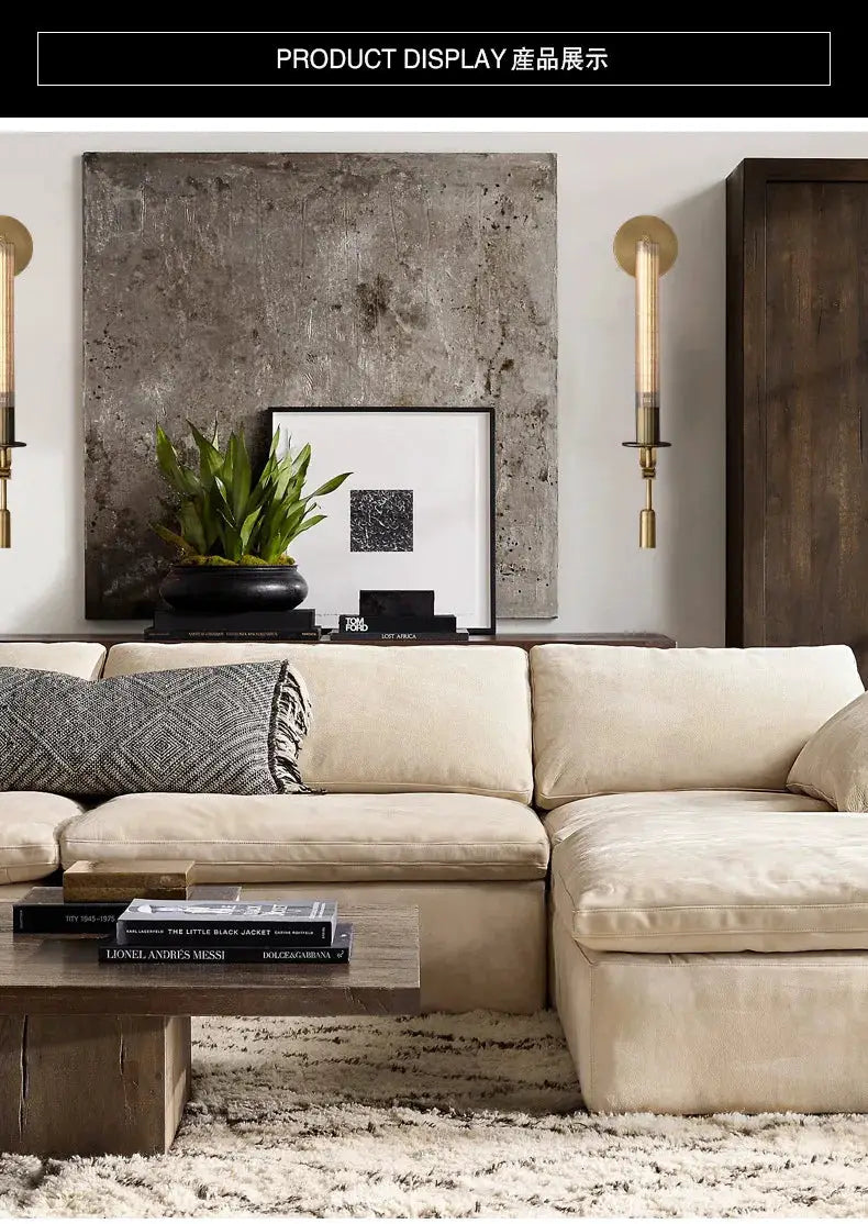 Modern copper wall sconce lamp pair with glass-tube accents flanking a textured art panel above a beige sofa.