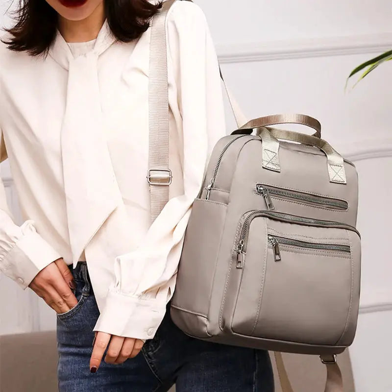 Women's gray waterproof Oxford backpack with multiple zip pockets and beige straps