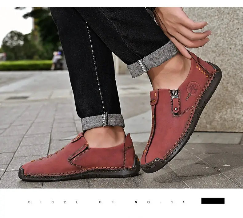 Handmade leather men's slip-on loafers in reddish-brown with moccasin stitching and black sole.