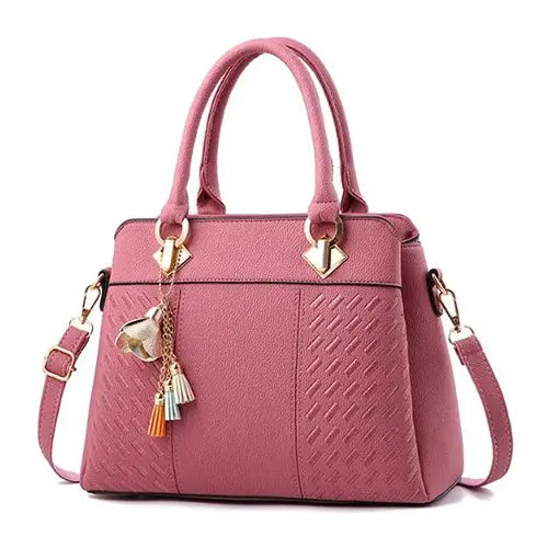 Pink PU leather handbag with top-handle, crossbody strap, and tassel charm by Simples Market