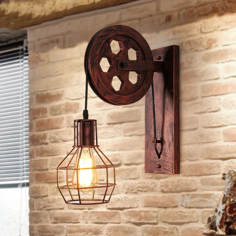 Vintage industrial wall sconce with pulley wheel, dark wood and metal cage surrounding Edison bulb