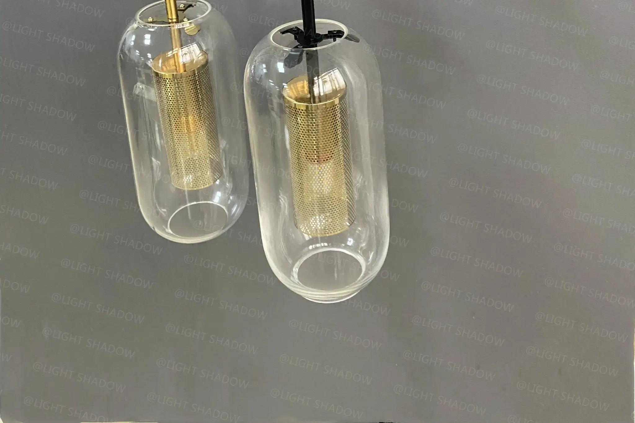 Pair of modern glass wall light sconces with brass mesh cylinders inside clear glass tubes