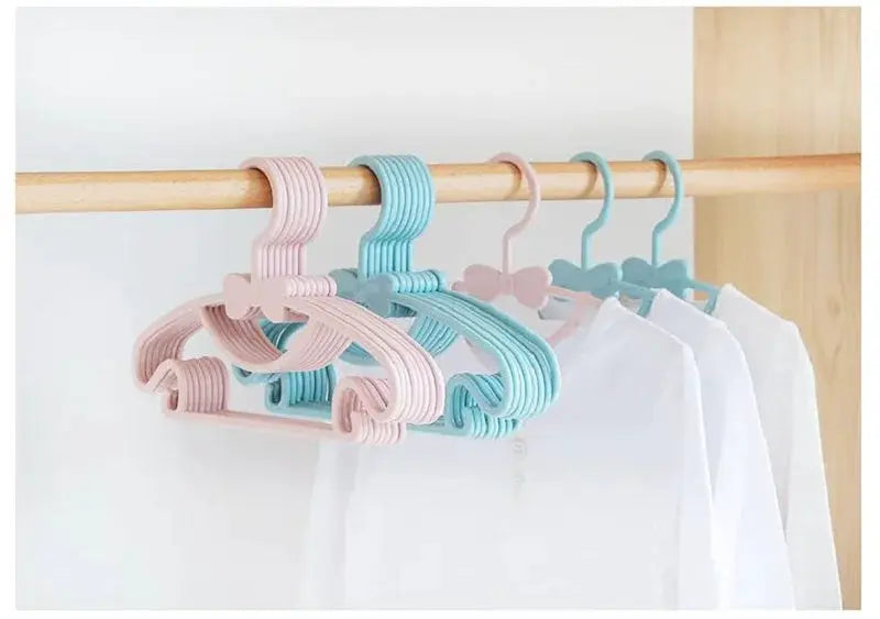Pastel plastic baby clothes hangers on a wooden rod; pink and blue set