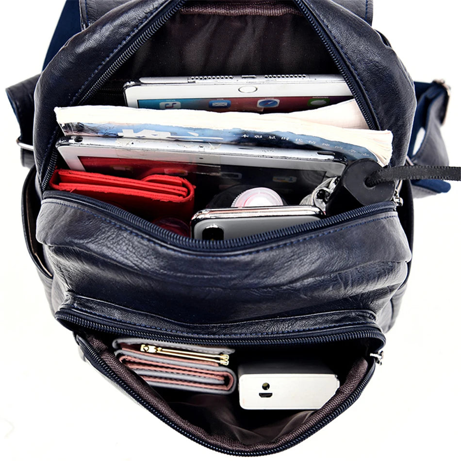Navy genuine leather backpack with multiple compartments, filled with a phone, wallet and papers