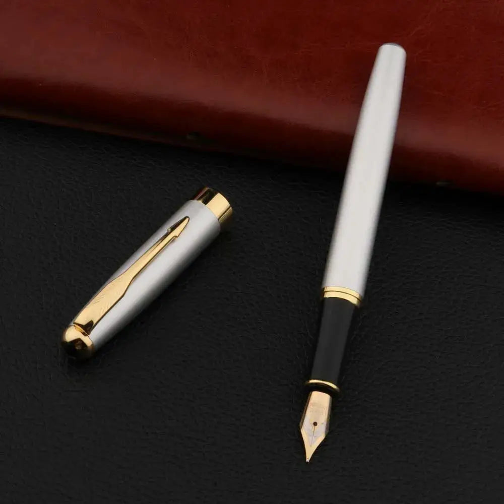 Fountain pen; white metal body with gold nib and trim, black grip, cap nearby on black surface