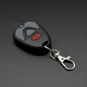 Garage door remote control by Simples Market, black fob with gray and red buttons and a metal keychain clip