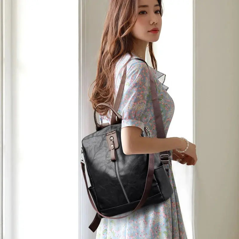Women’s anti-theft backpack in black PU leather with brown top handle and crossbody strap