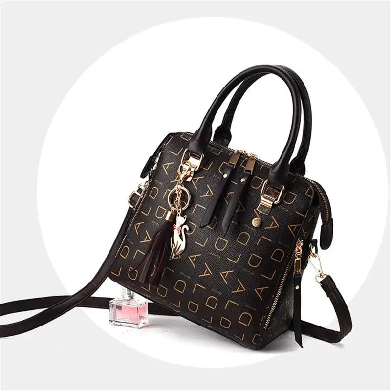 Black PU leather handbag with tassel, top-handle design, gold-tone hardware, and English-letter pattern