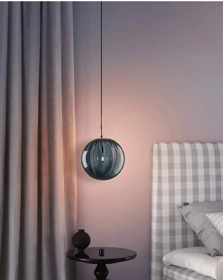 Modern LED glass ball pendant light in blue, Nordic style, hanging over the bed in a bedroom