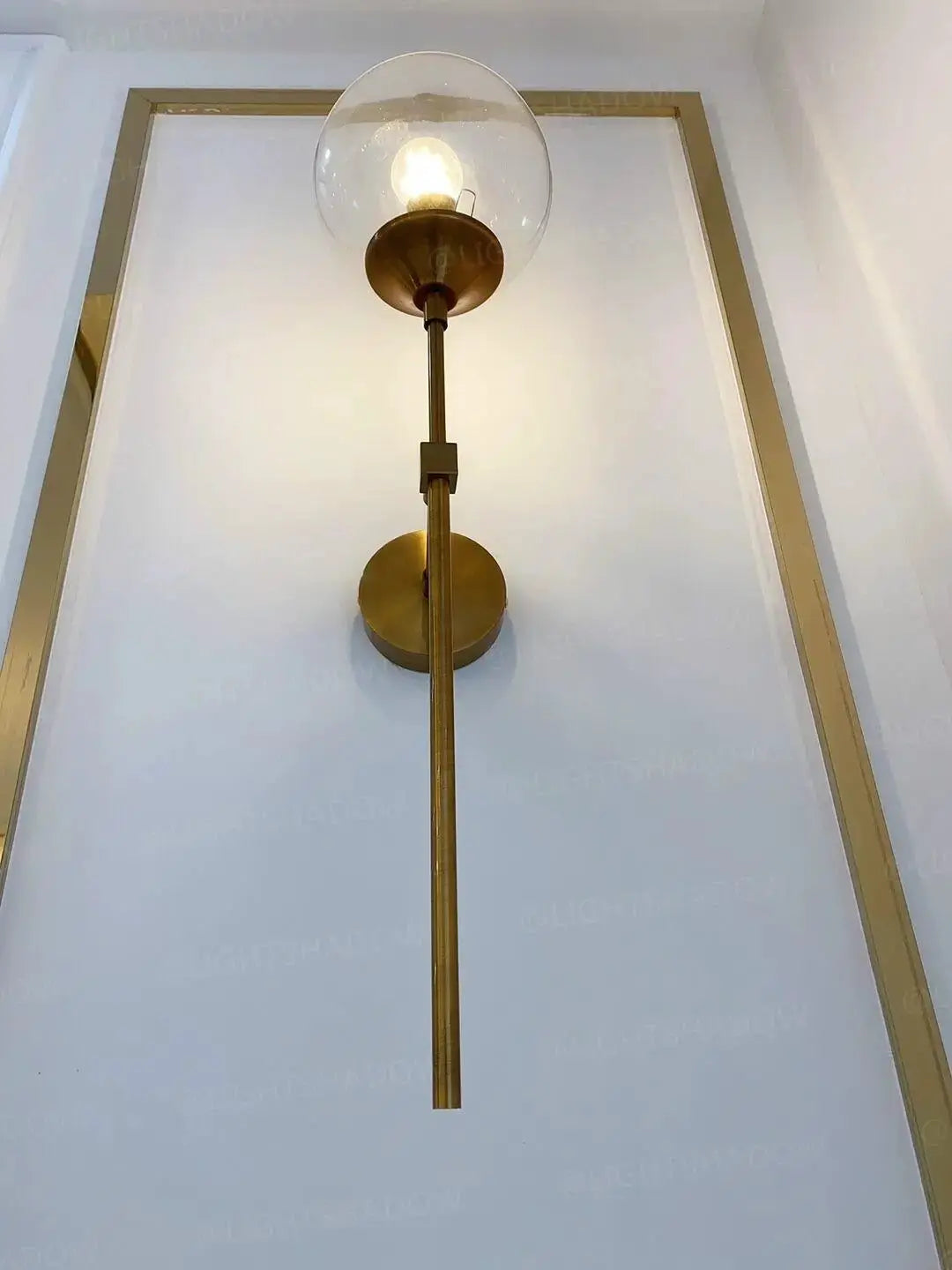 Modern glass wall lamp with a clear globe shade and brass body, Nordic-style wall sconce for bedroom or living room.